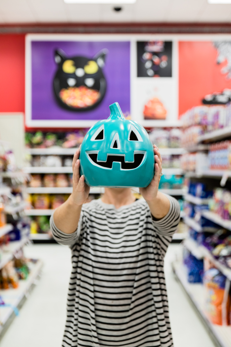 A person holding up a teal jack o lantern.