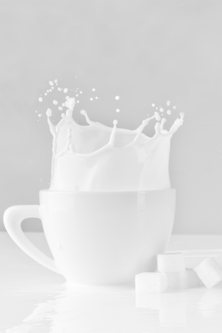 a white mug with milk splashing out.
