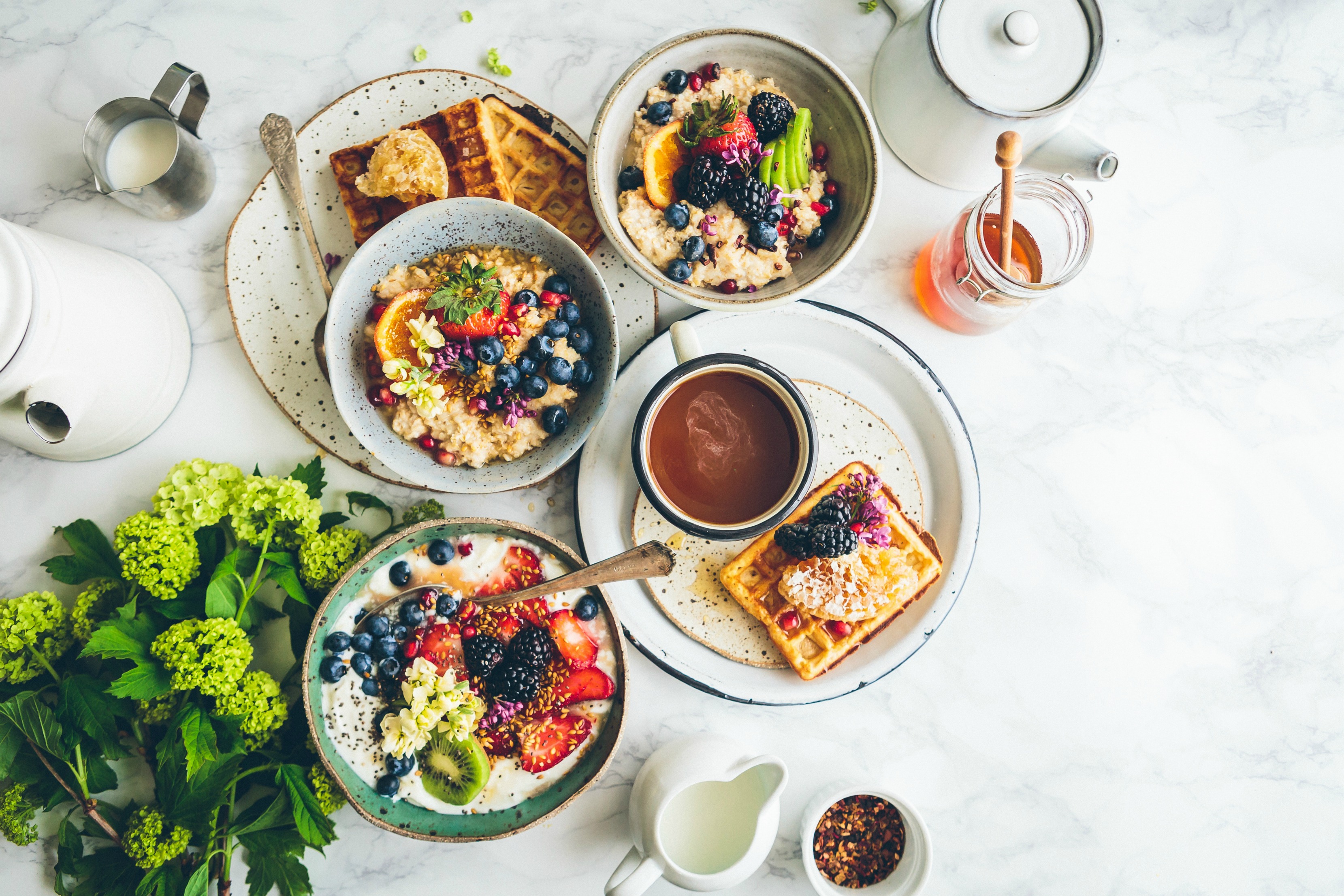 a tablescape filled with bowls of oatmeals and plates of waffles.