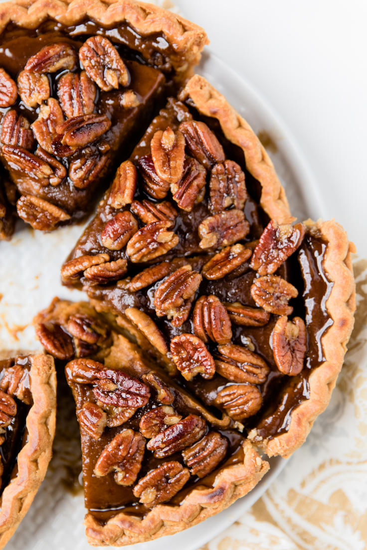 Slices of Vegan pumpkin pie with a pecan topping on a white plate.