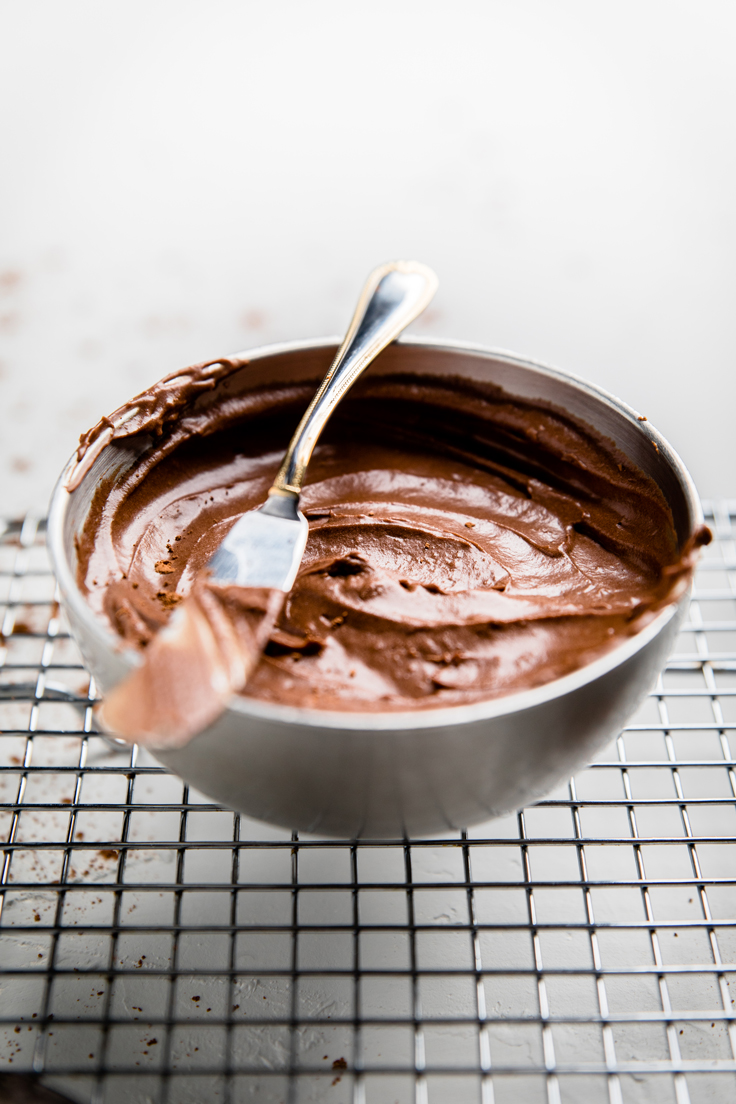 a bowl of dairy free chocolate frosting with a knife laying on top.