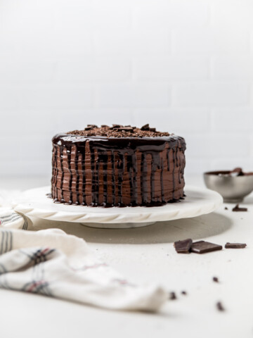 a triple layer dairy free chocolate cake uncut on a marble cake stand.