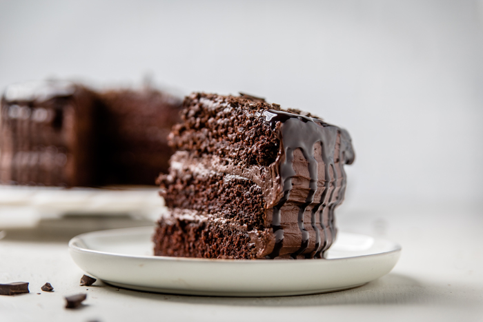 a slice of triple layered dairy free chocolate cake on a plate.