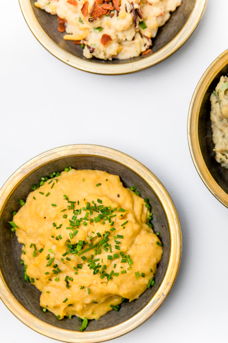 a bowl of dairy free mashed potatoes with cheddar topping and chives.