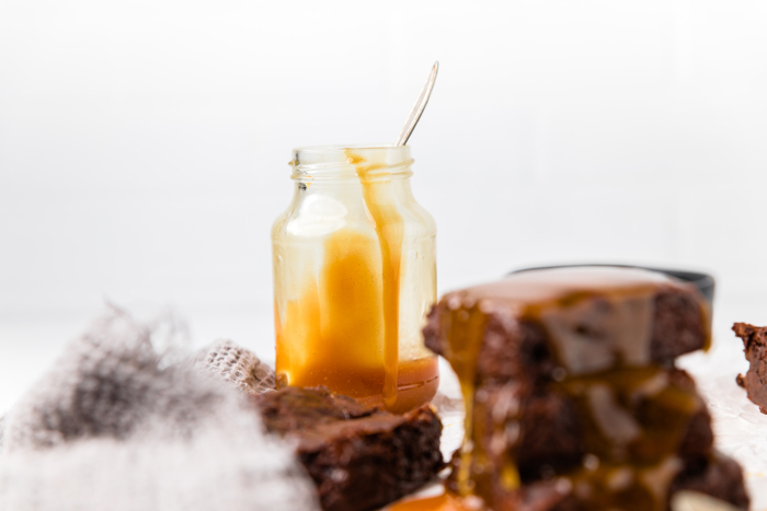 a jar of caramel next to a stack of dairy free brownies.