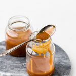 two jars and a spoon of dairy free caramel sauce.