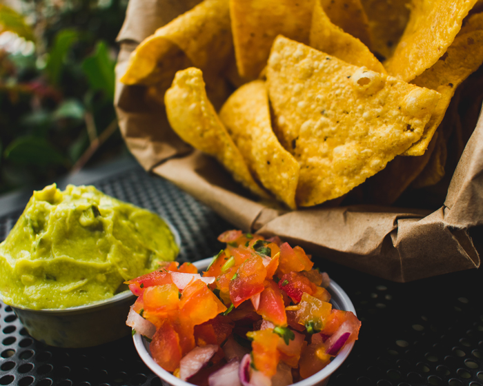a bowl of tortilla chips, a bowl of salsa, and a bowl of guacamole.