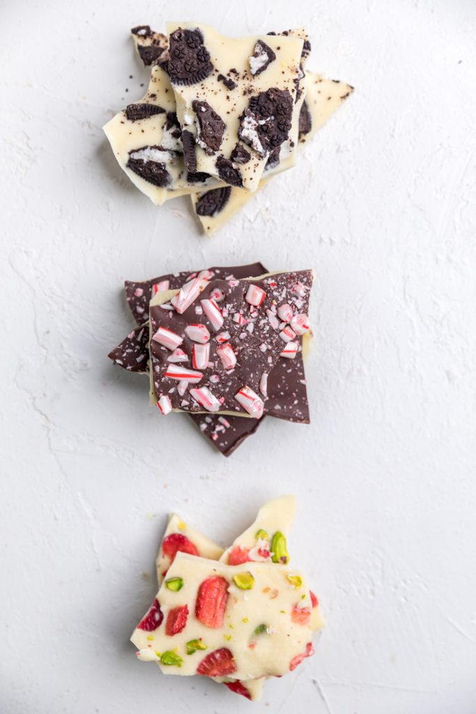 three types of homemade dairy free chocolate bark on a white table.