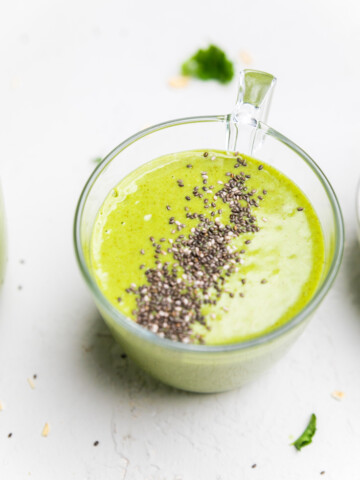 A glass of dairy free green smoothie topped with chia seeds.