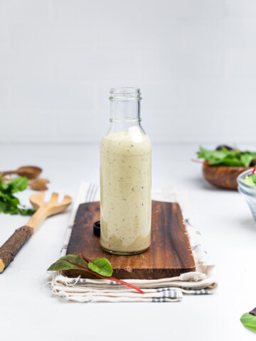 a bottle of dairy free caesar dressing on a wooden board.