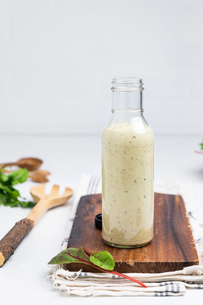 a bottle of dairy free caesar dressing on a wooden board.
