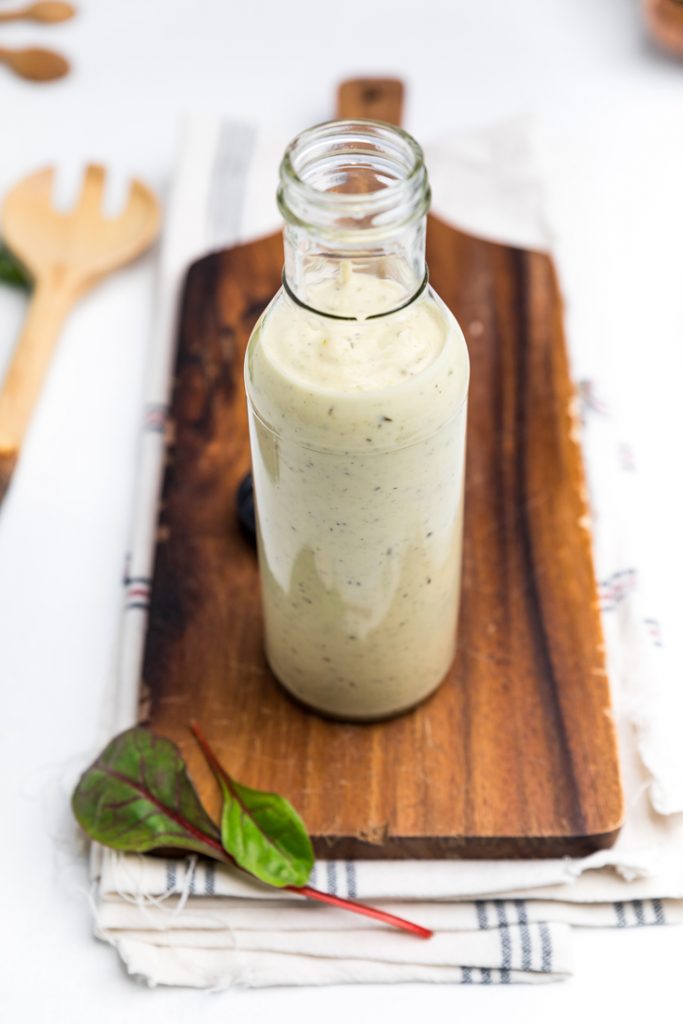 a bottle filled with dairy free caesar dressing on a wooden board.