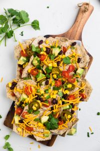 A board of dairy free nachos and fresh toppings.