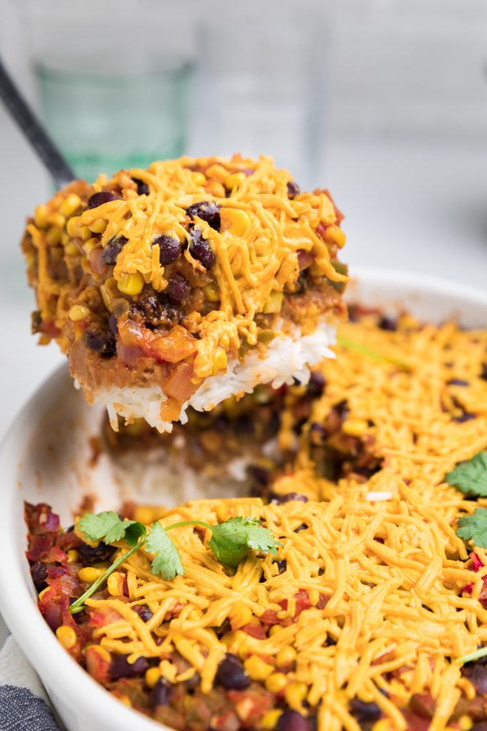 A serving of Vegan taco casserole being held above the serving dish.