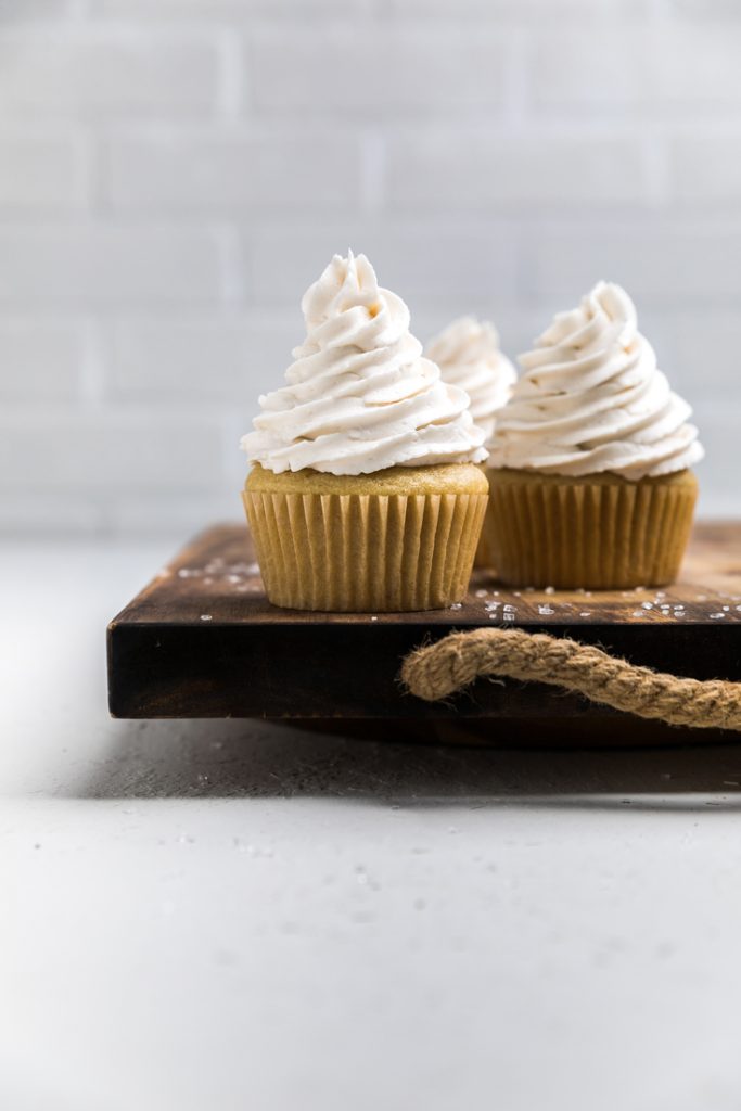 Three Dairy free vanilla cupcakes with spiraled vegan vanilla frosting on top.