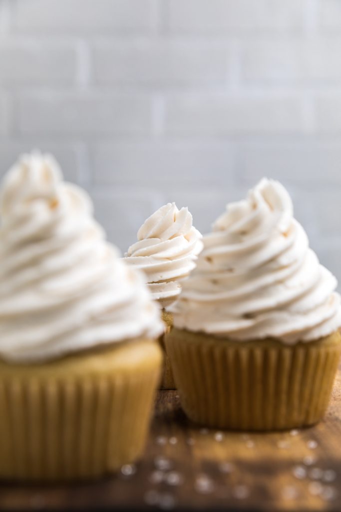 three dairy free vanilla cupcakes with vanilla swirled frosting.