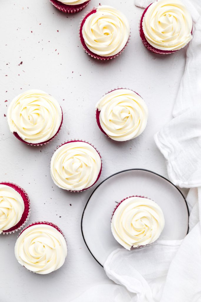 a table of dairy free red velvet cupcakes with cream cheese frosting.