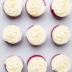 tops of 9 dairy free red velvet cupcakes with cream cheese frosting.
