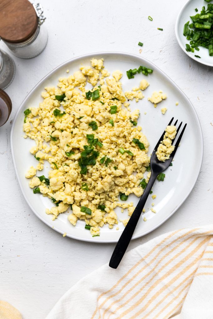a plate of vegan scrambled eggs topped with green onions.