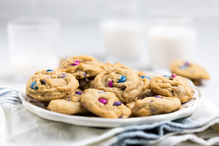 a plate of vegan m and m cookies with blue and pink candies.