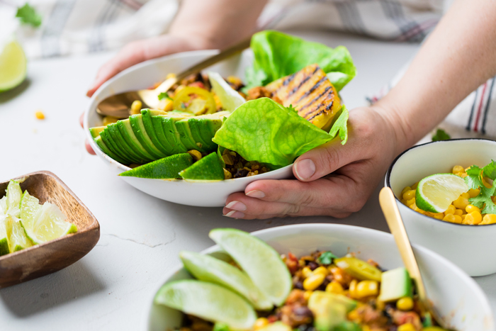 hands laying down a bowl of chorizo vegan burrito onto a table.