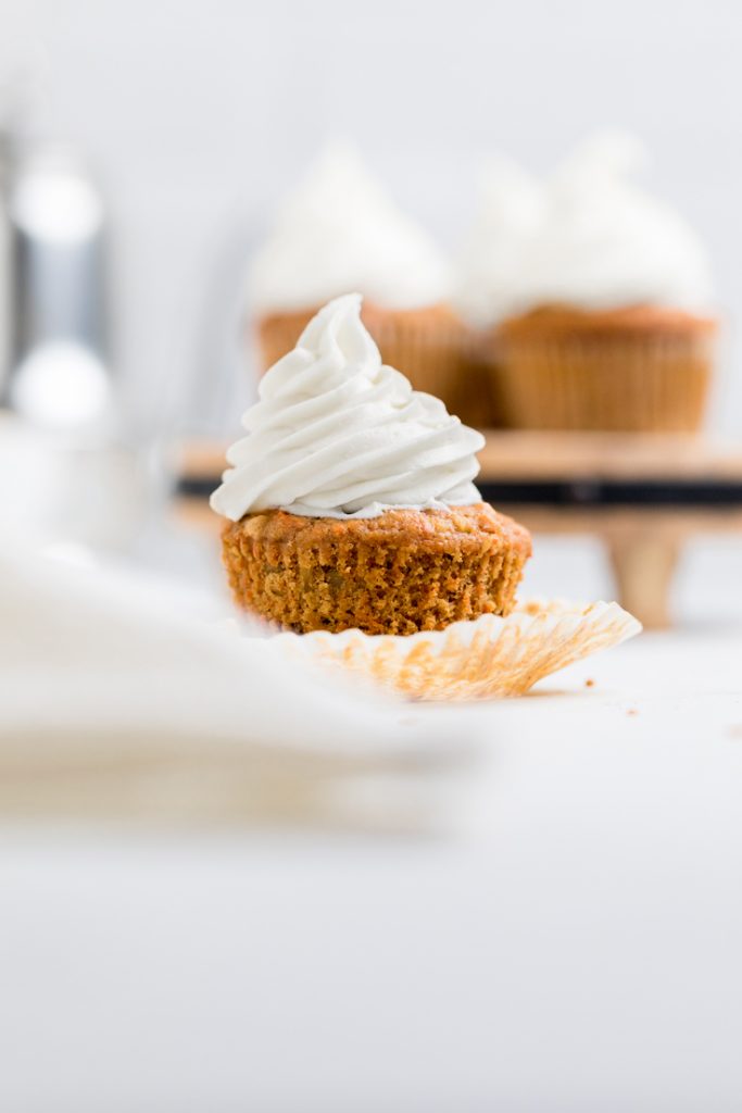 A close up of a dairy free carrot cake cupcake laying on open wrapper.
