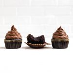 three dairy free chocolate cupcakes on a table.