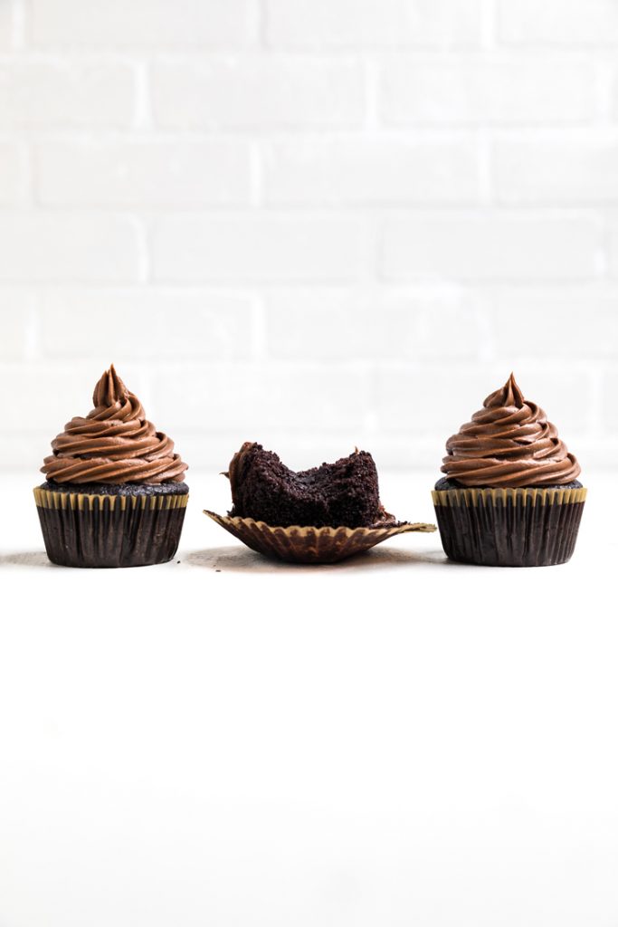 3 Chocolate vegan cupcakes with one in the middle bitten.