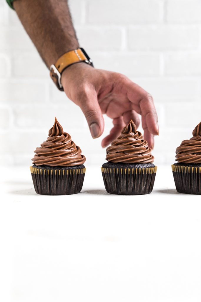 a hand reaching for a dairy free chocolate cupcake.
