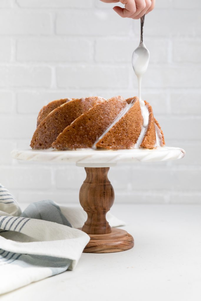 Dairy free lemon pound cake with lemon glaze being drizzled over.