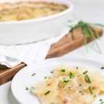 a serving dish and a plate of vegan scalloped potatoes.