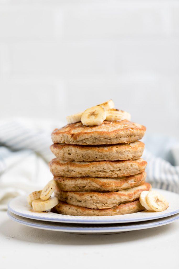 a white plate filled with vegan banana pancakes.