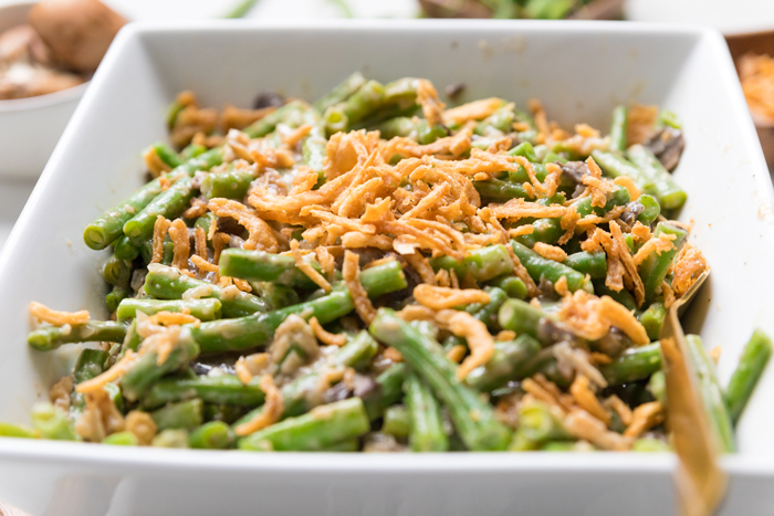 creamy vegan green bean casserole topped with fried onions in a white dish.