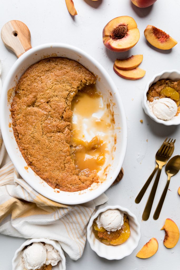 A dish of vegan peach cobbler with a spoonful missing.