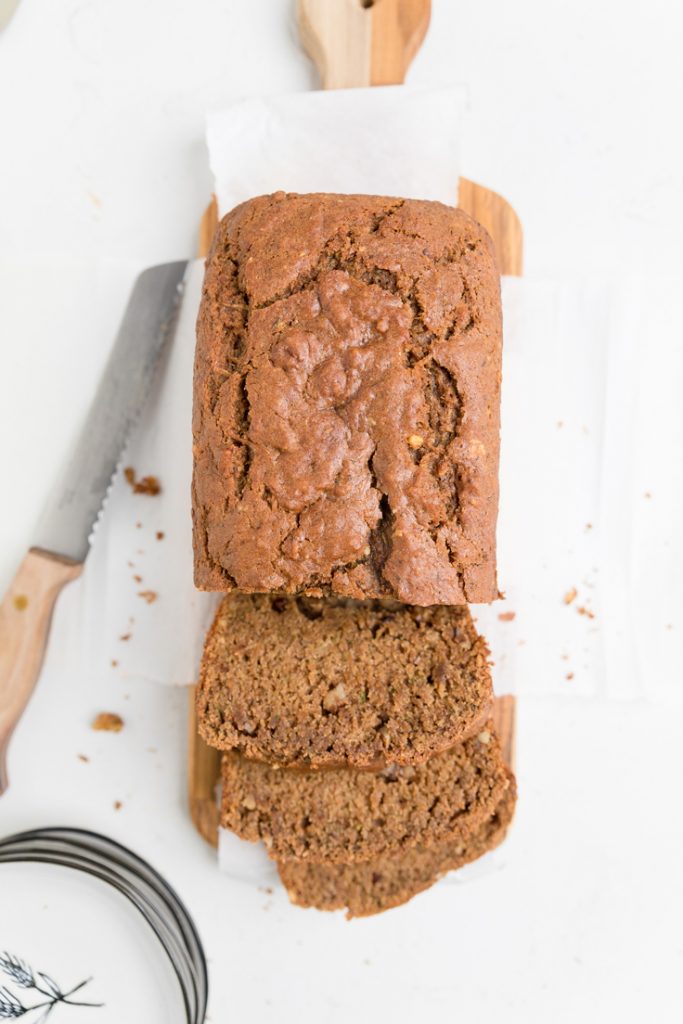 A loaf of vegan zucchini bread with two pieces sliced.