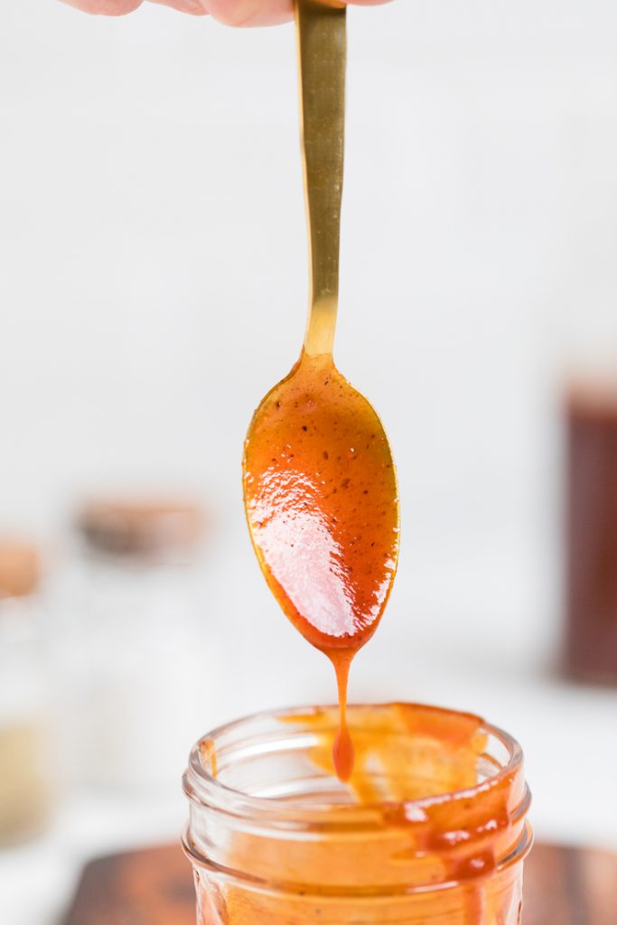 A spoon with homemade vegan bbq sauce drizzling off.
