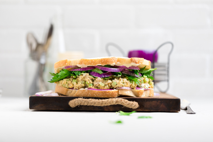 A chickpea salad sandwich on a cutting board.