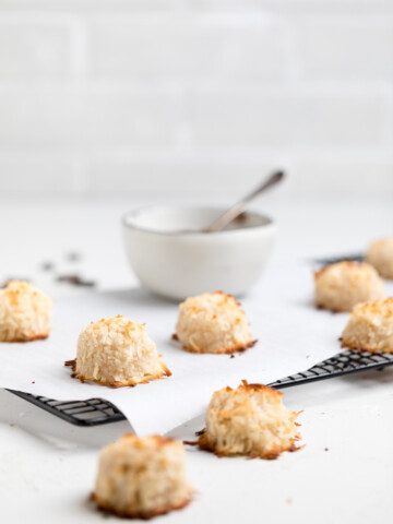 a batch of vegan coconut macaroons on a parchment lined wire rack.