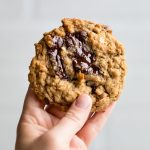 a hand holding one vegan oatmeal chocolate chip cookie.
