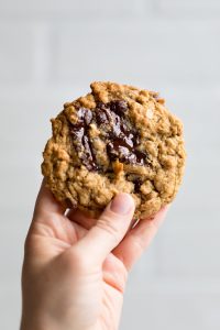 a hand holding one vegan oatmeal chocolate chip cookie.