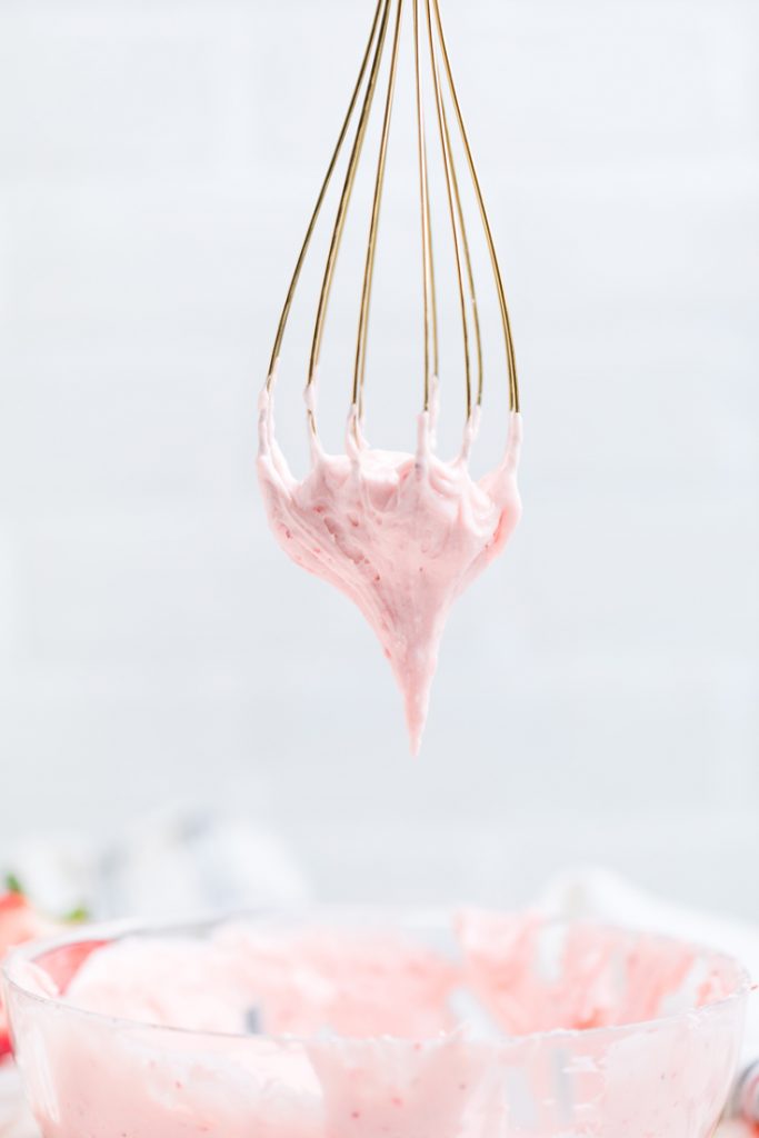 a gold whisk upside down with Vegan strawberry buttercream frosting. 