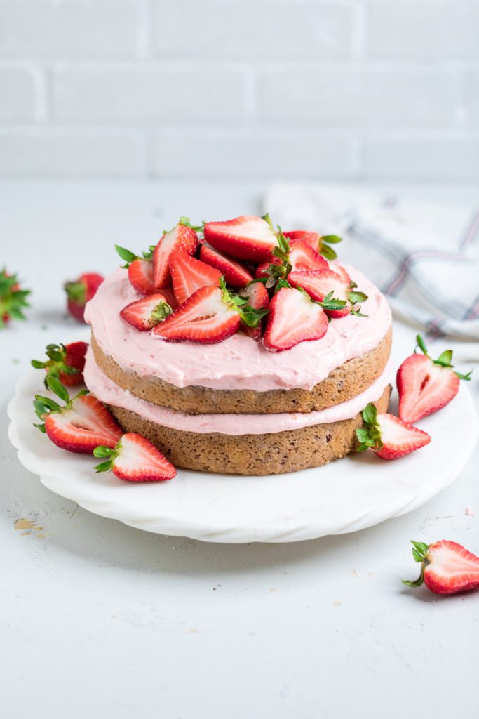 two layer Vegan strawberry cake with fresh sliced strawberries and vegan strawberry buttercream on top. 
