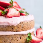 a double layered vegan strawberry cake with strawberry buttercream frosting and fresh strawberry slices.