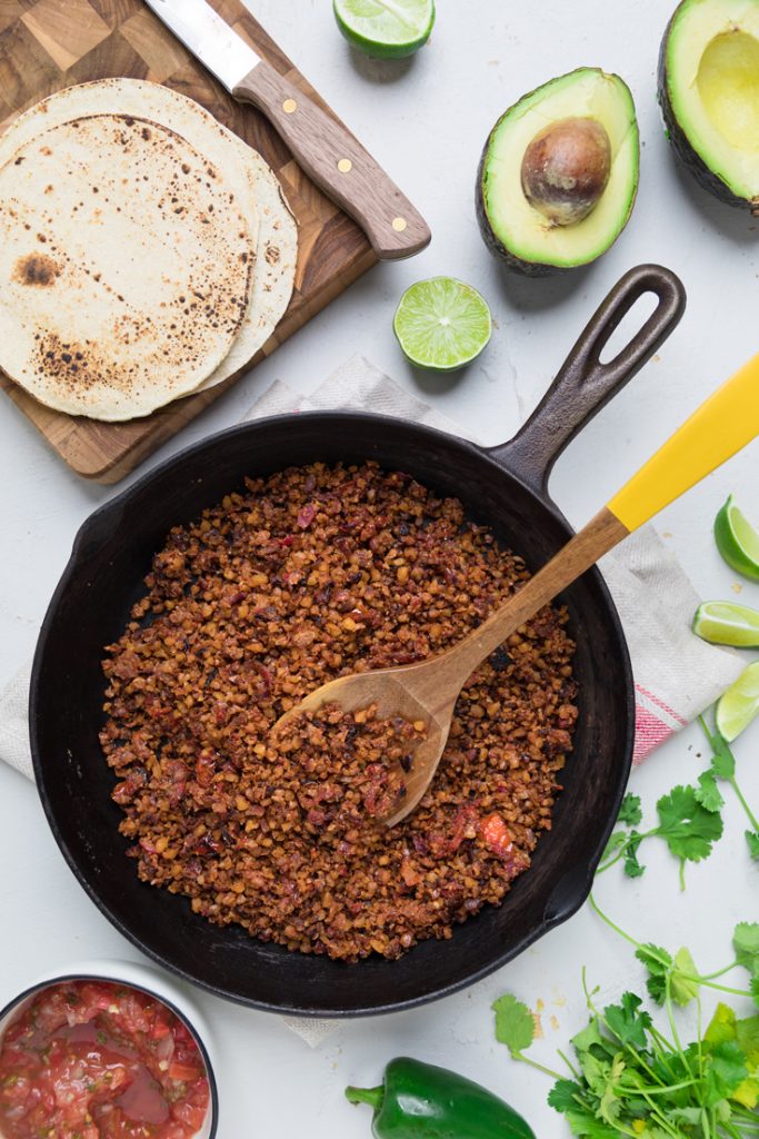 Vegan walnut taco meat in a skillet with a wooden spoon.