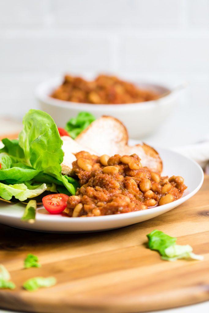 a plate with salad, buttered bread and vegan baked beans.