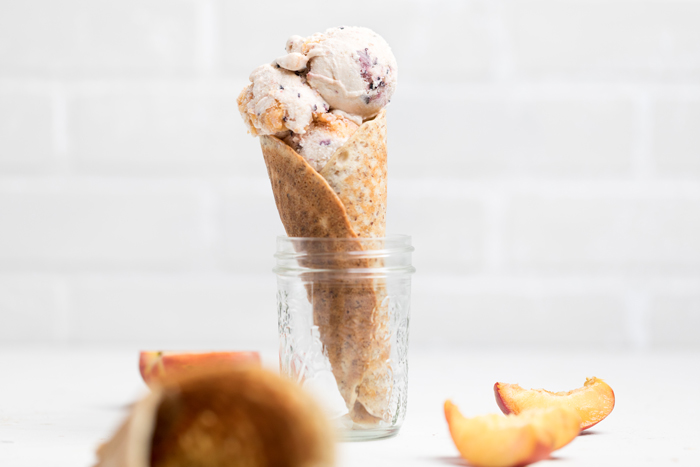 an ice cream cone filled with vegan vanilla blueberry peach ice cream resting in a jar.