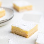 a white table with a vegan lemon bar topped with powdered sugar.