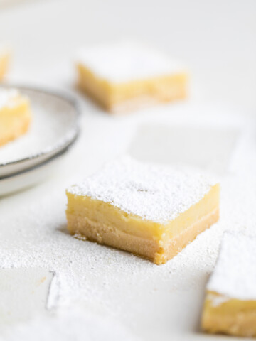 a white table with a vegan lemon bar topped with powdered sugar.