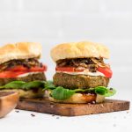 two vegan lentil burgers lying on a wooden board.