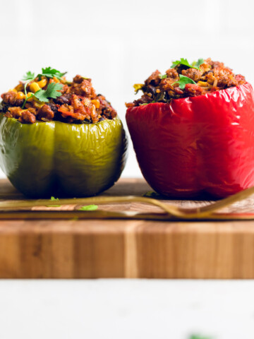 two vegan chorizo mexican stuffed peppers on a wooden board.